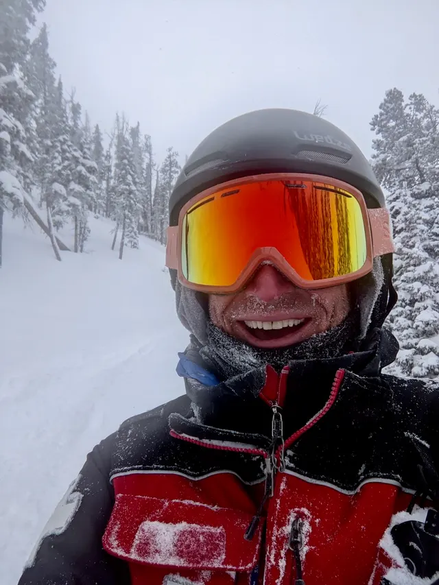 Patroller wearing ski goggles in falling snow