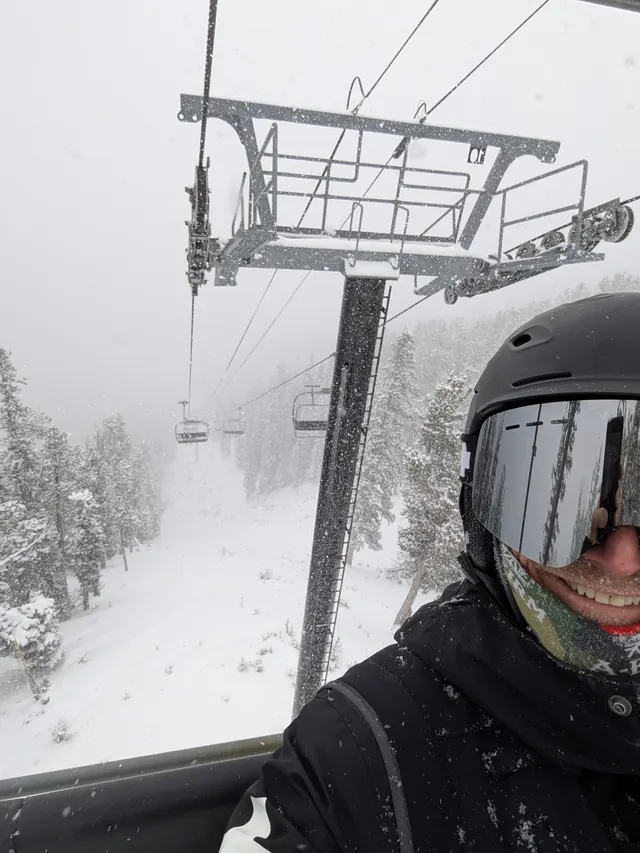 Patroller on a chairlift in falling snow