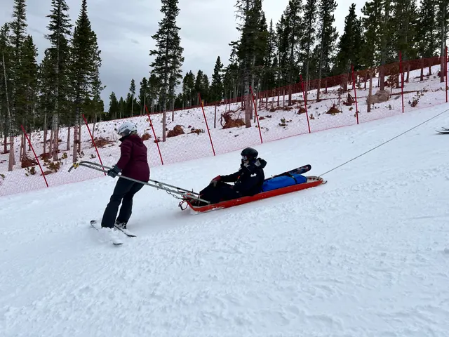 Patroller leading a rescue toboggan down a slope