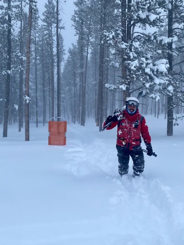 Patroller skiing through falling snow