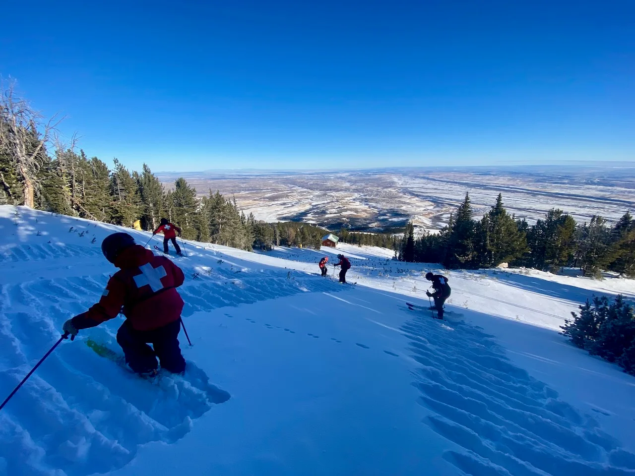 Patrollers descending a run above the valley